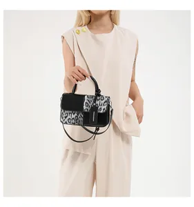 Detailansicht der Handtasche mit Leopardenmuster, schwarzem Griff und Anhänger.