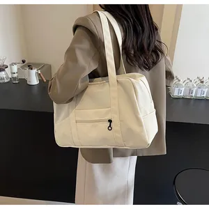 Large cream nylon travel tote bag shown on model in a modern lifestyle setting