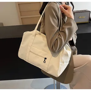 A professional model carrying a large cream nylon tote bag for travel or gym use.