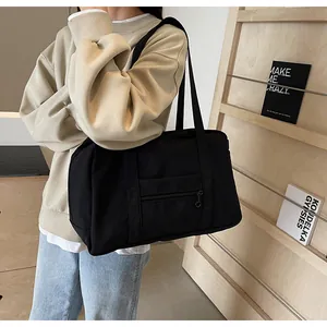 Large black nylon tote bag shown in a lifestyle setting for gym and travel usage