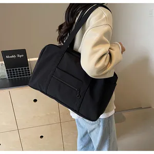 Side view of model carrying large black nylon tote bag on shoulder in minimalist room
