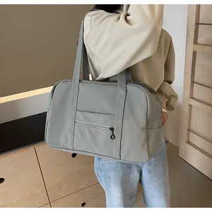 Side view of grey nylon large capacity tote bag worn by model in a bright setting