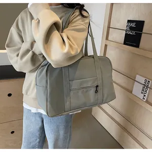 Large capacity nylon travel tote bag in sage green color carried by model in detail view