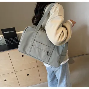 Stylish large sage green nylon travel bag with shoulder straps shown in a lifestyle setting.