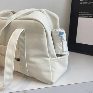Close-up detail of cream nylon tote bag featuring grid texture and a side pocket.