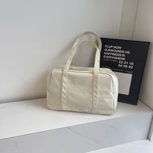 Minimalist off-white nylon duffel bag for travel and gym in lifestyle setting