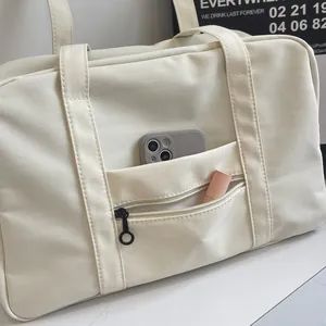 Detailed macro view of the front zipper pocket on a cream nylon travel tote bag
