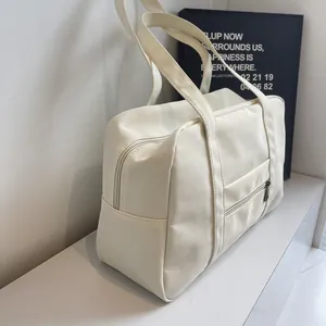 Side view of a beige nylon travel tote bag showing side pockets and metal zippers