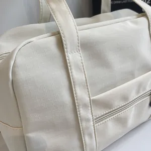 Close-up of off-white ripstop nylon travel bag showing durable zipper and stitching details