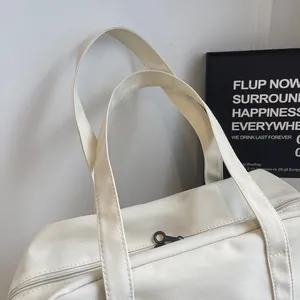 Detail shot of white nylon travel tote bag straps and zipper area.