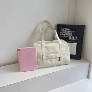 Large capacity cream nylon travel bag next to a pink tablet for size comparison