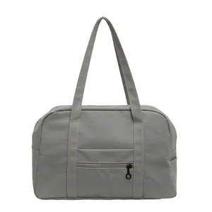 Front view of a minimalist grey nylon tote bag showing zipper pockets and sturdy straps.