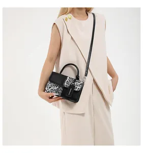 Modell zeigt eine schicke Handtasche mit grauem Leopardenmuster und schwarzen Details