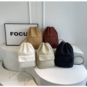 Group of lightweight nylon drawstring bucket backpacks in five colors on a white display