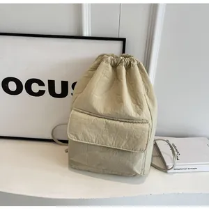 Detail of minimalist nylon drawstring bucket backpack in beige with front flap pocket.