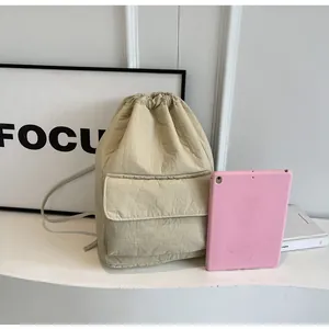 Minimalist lightweight beige nylon drawstring backpack shown next to a tablet for scale