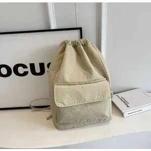 Lightweight beige nylon drawstring bucket backpack featuring a front flap pocket detail