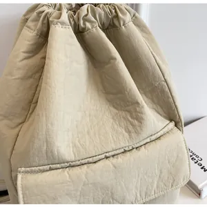 Close-up of light beige nylon drawstring backpack with front flap pocket detail