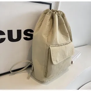 Detail shot of a minimalist beige nylon drawstring bucket backpack with a front pocket