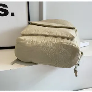 Detailed bottom view of a lightweight beige nylon backpack showing its crinkled texture