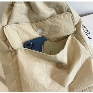 Close-up detail of beige nylon drawstring backpack showing front pocket storage capacity