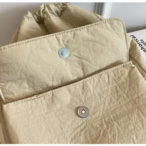 Detailed macro view of the magnetic button closure on a cream quilted nylon backpack