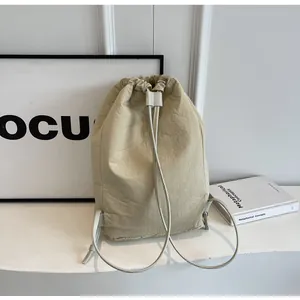 Minimalist beige nylon drawstring backpack bucket bag shown in a lifestyle indoor setting