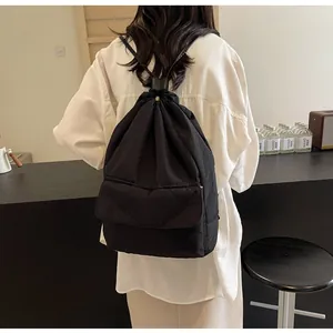 Back view of a lightweight black nylon drawstring bucket backpack on a female model