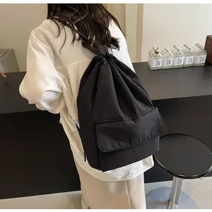 Large capacity black nylon drawstring backpack shown on model in minimalist scene