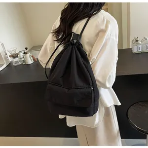 Back view of a stylish black lightweight nylon drawstring backpack worn by a model