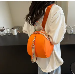 Vue arrière d'un mini-sac à dos orange vif en forme de coquille avec bretelles fleuries.