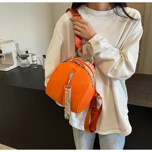 Vue détaillée du mini sac à dos orange en forme de coquille avec bretelles tissées