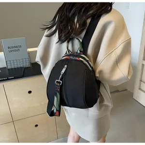 Vue arrière d'un petit sac à dos noir en forme de coquille porté par un mannequin dans une pièce