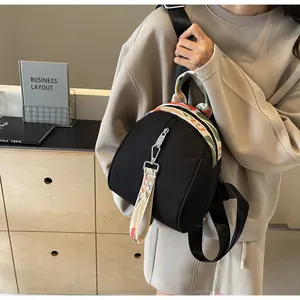 Vue de côté d'un mini sac à dos noir en forme de coquille avec sangles brodées
