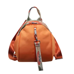 Gros plan détaillé d'un sac à dos orange vif en forme de coquille à sangles décorées.