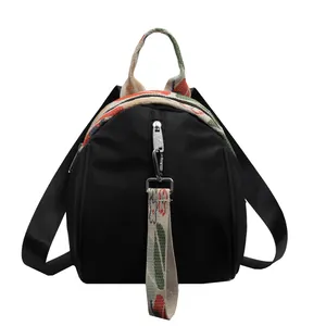 Vue frontale détaillée d'un mini sac à dos noir avec des bretelles en toile tissée colorée