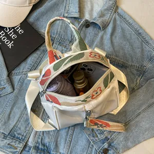 Sac à dos coquillage blanc élégant avec broderies florales, ouvert avec accessoires.