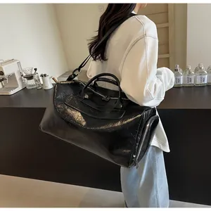 Bolso de viaje grande de cuero arrugado negro llevado por una modelo en una cafetería