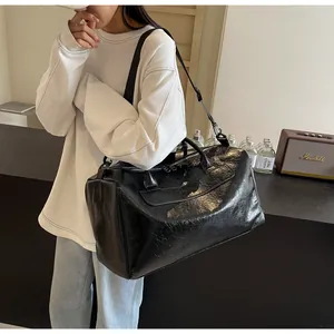 Primer plano de una gran bolsa de viaje negra llevada al hombro por una modelo joven.
