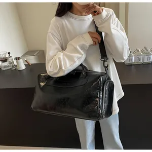 Primer plano del bolso de viaje de cuero arrugado negro llevado por una modelo en café