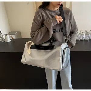 Bolsa de viaje deportiva grande en plata metalizada sostenida por una modelo