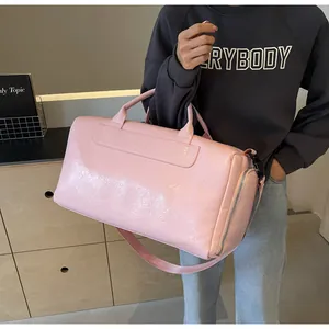 Modelo con una bolsa de viaje rosa de cuero charol con asas resistentes y correa