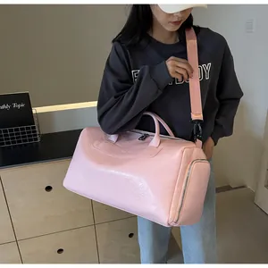 Modelo asiática llevando un bolso de viaje rosa brillante en una escena de interior