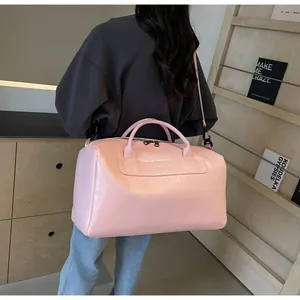 Vista trasera de una persona que lleva un gran bolso de viaje de cuero rosa brillante.