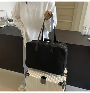 Detail der schwarzen Segeltuch-Reisetasche auf einem weißen Koffer in Lifestyle-Umgebung.