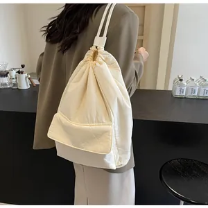 Detailed view of a cream nylon drawstring bucket backpack with a front flap pocket.