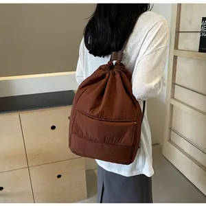 Modern brown nylon drawstring backpack for women shown in a lifestyle back view posture.