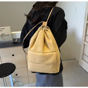 Model wearing a yellow nylon drawstring bucket backpack with a minimalist design