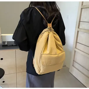 Back view showing the fit and texture of the minimalist yellow nylon drawstring backpack