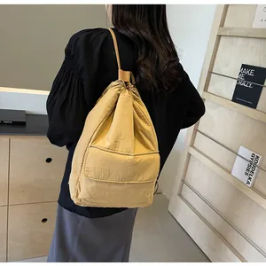 Yellow nylon drawstring bucket backpack worn on back in lifestyle setting